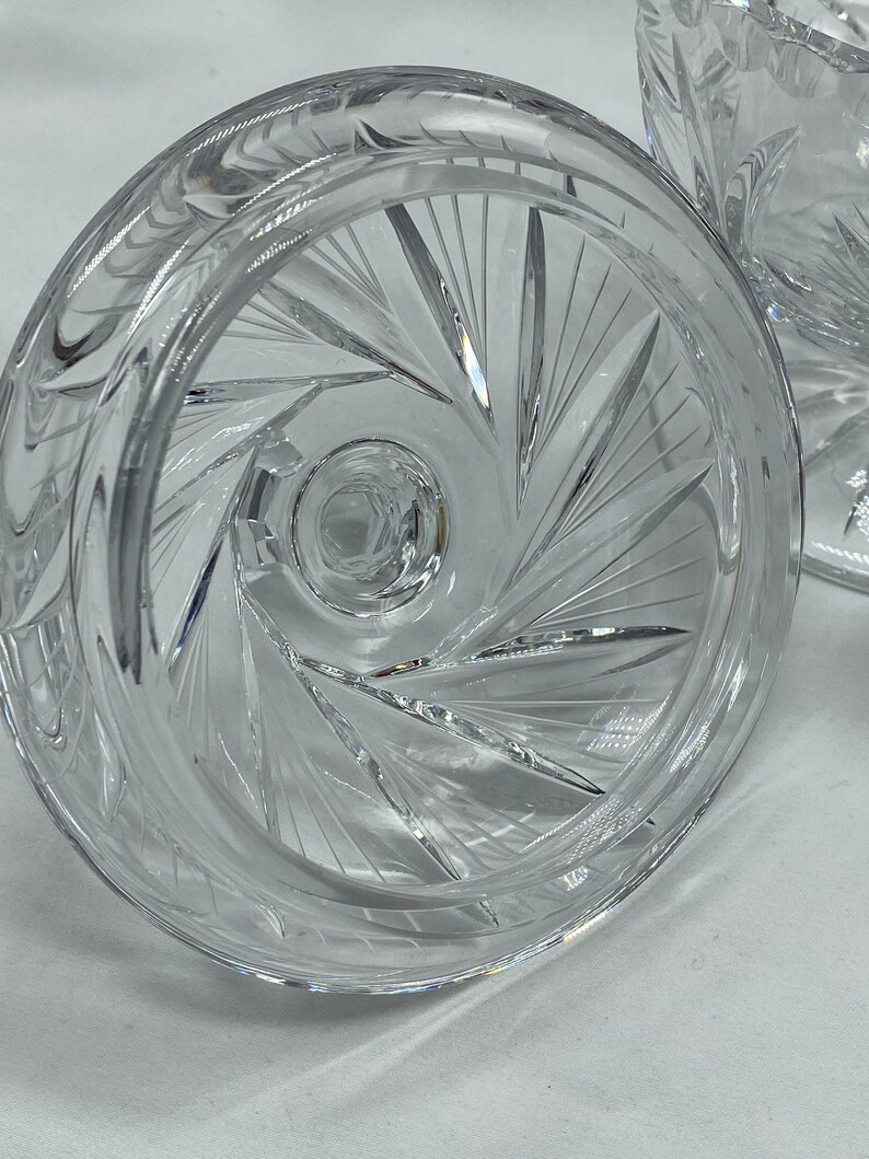 May include: Close-up of the underside of a clear glass bowl with a cut glass design. The bowl has a wide, flat base and a deep, round centre.