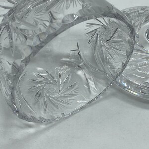 May include: A clear glass cake stand with a cut crystal design. The stand has a round base and a domed top.