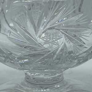 May include: A clear glass bowl with a cut glass design. The bowl has a starburst pattern in the centre and a scalloped edge.