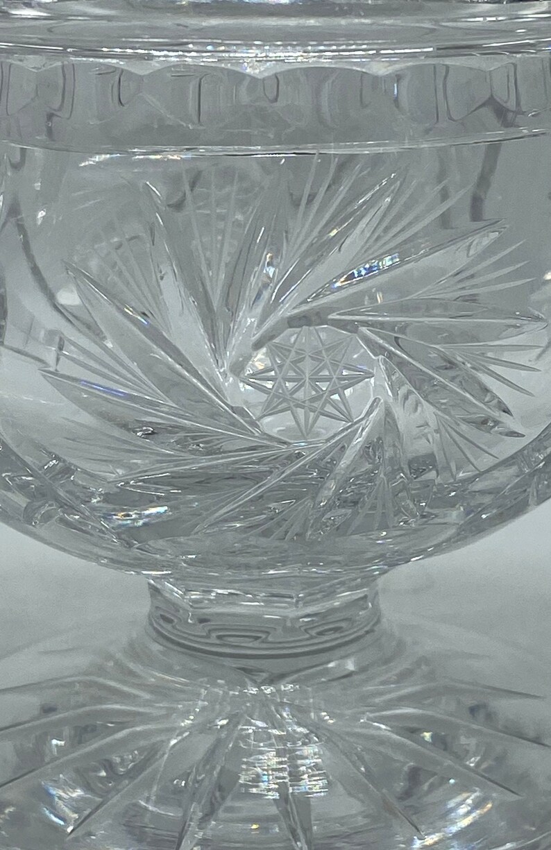 May include: A clear glass bowl with a cut glass design. The bowl has a starburst pattern in the centre and a scalloped edge.