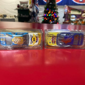 Puede incluir: Dos coches de carreras Racing Champions de fundición a presión en cajas de plástico transparente. Uno es azul, amarillo y blanco con la marca "NAPA". El otro es amarillo y azul con la marca "Goodyear". Ambos están etiquetados como "Program Car".