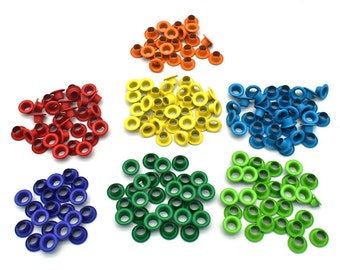May include: Assortment of colorful metal eyelets in red, orange, yellow, blue, and green. The eyelets are arranged in six piles on a white background.