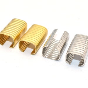 May include: Four metal U-shaped clasps, two gold and two silver, with a ribbed texture.