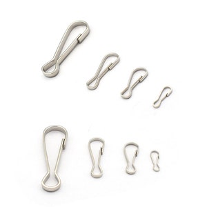 May include: A set of seven silver metal trigger snaps in various sizes. The snaps are commonly used for attaching keychains, lanyards, and other accessories.