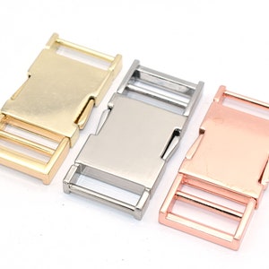 May include: Three metal buckles in gold, silver, and rose gold. The buckles are designed for use on straps or belts.