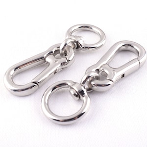 May include: Two silver metal swivel clasps with a ring on one end. The clasps are designed for attaching to bags, straps, or other items.