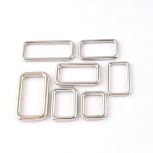 May include: A set of seven silver metal rectangular rings of varying sizes.