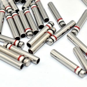 May include: A pile of silver metal tubes with red, white, and black stripes. The tubes are about 1 inch long.