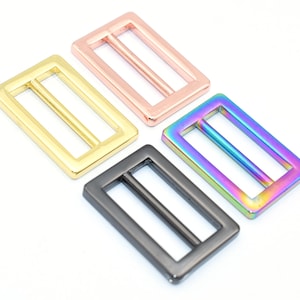 May include: Four metal slider buckles in different finishes: gold, rose gold, black, and iridescent.