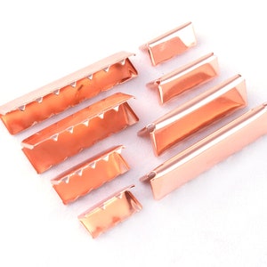 May include: A set of seven rose gold metal strap ends in various sizes. The strap ends have a scalloped edge and are ideal for leather straps.