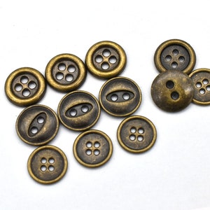 May include: A collection of 10 antique gold-toned metal buttons with various designs, including four-hole, two-hole, and oval-shaped buttons.
