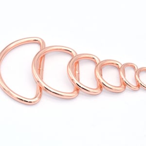 Puede incluir: Un juego de seis anillos en D de color oro rosa en varios tamaños. Los anillos son de metal y tienen un acabado liso.