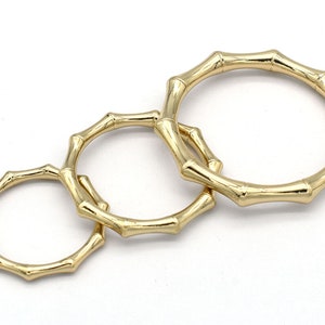 May include: Three gold rings in a bamboo style, each of a different size. The rings are interlocked and made from a smooth, shiny metal.