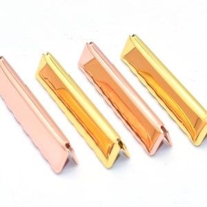May include: Four metal corner protectors in two-tone gold and rose gold. The protectors are angled and have a decorative edge.