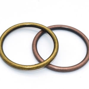 May include: Two metal rings, one gold and one copper, are interlocked. The rings are smooth and have a slightly worn finish.