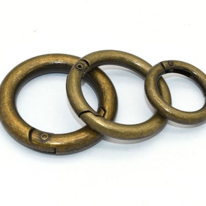 May include: Three antique gold-toned metal key rings of different sizes. The rings are linked together.