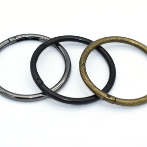 May include: Three metal rings in different finishes: black, silver, and gold. The rings are open and have a swivel clasp.
