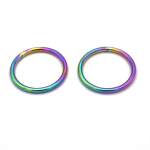 May include: Two rainbow colored metal rings. The rings are smooth and shiny.
