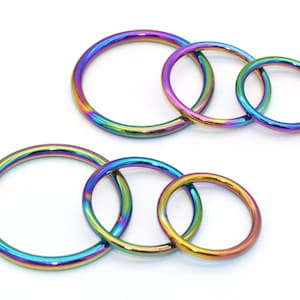 May include: Set of five iridescent metal jump rings in various sizes. The rings are a rainbow of colors, including blue, green, purple, and gold.