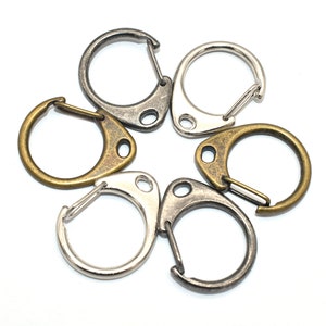May include: Five silver and gold key rings with a swivel clasp. The key rings are arranged in a circle.