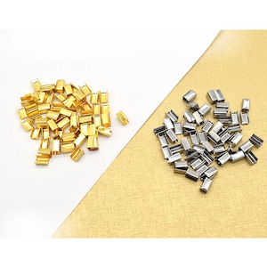 Puede incluir: Dos pilas de tapones de extremo de metal, una pila es dorada y la otra es plateada.