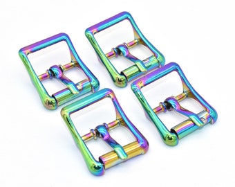 Op de afbeelding: Vier regenboogkleurige metalen riemgespen met een iriserende afwerking. De gespen zijn vierkant en hebben een gladde afwerking.