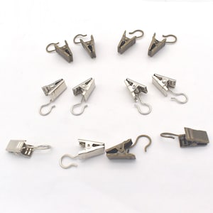May include: A set of 12 curtain clips, with 6 silver and 6 bronze clips. Each clip has a hook on the end for hanging curtains.