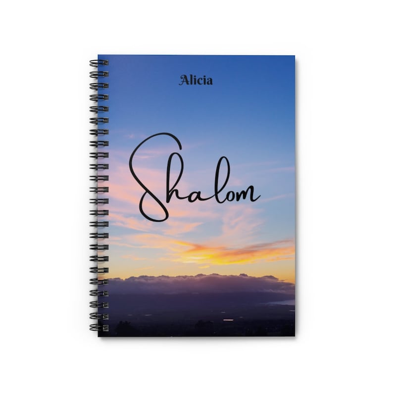 Peut inclure: Un carnet &agrave; spirales avec un fond de ciel de coucher de soleil. Le texte "Shalom" est &eacute;crit en cursive sur la couverture. Le nom "Alicia" est imprim&eacute; en noir en haut de la couverture.