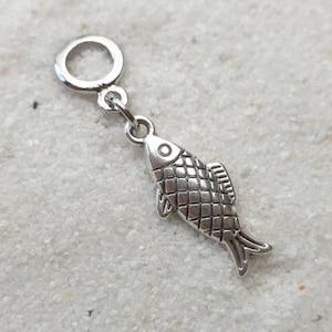 Op de afbeelding: Zilveren bedel in de vorm van een vis met een getextureerd lichaam. De bedel heeft een lus aan de bovenkant om aan een armband of ketting te bevestigen.