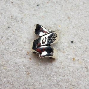 Puede incluir: Anillo de plata con una banda retorcida que dice "LOVE".