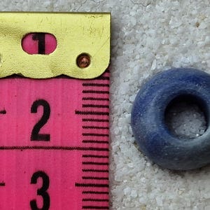 May include: A blue ceramic bead with a hole in the center. The bead is about 1 inch in diameter.