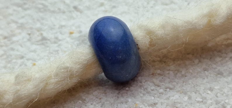 May include: A smooth, round, blue glass bead with a slightly textured surface.