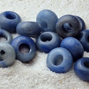 May include: A collection of blue and white gemstone beads with a hole in the center. The beads are smooth and polished, and they have a natural, organic look.