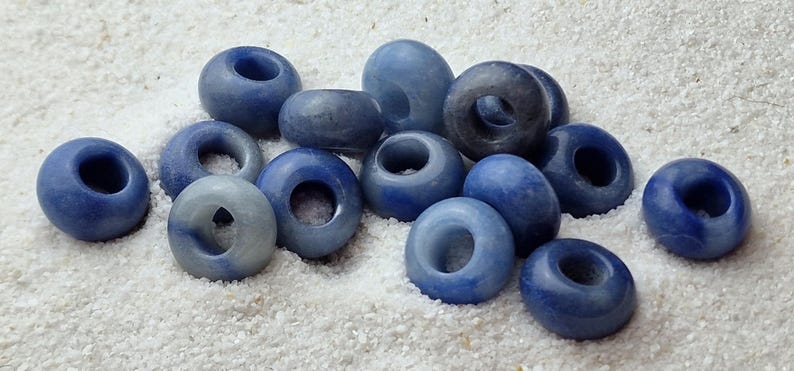 May include: A collection of blue and white gemstone beads with a hole in the center. The beads are smooth and polished, and they have a natural, organic look.