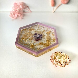 May include: A hexagonal tray with a purple rim and gold flakes embedded in the clear resin. The tray has a cluster of small purple stones in the center.