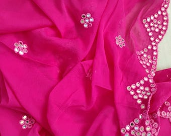 May include: A vibrant hot pink fabric scarf or shawl featuring scattered floral-shaped clusters of small circular mirrors. The edge of the fabric is heavily embellished with a wide, dense border of the same reflective mirror work.