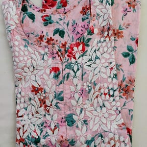 May include: A light pink floral print outfit, comprising a top and trousers. The top features a scoop neckline and white floral embroidery. The floral pattern incorporates red, pink, and green hues, offering a vibrant and feminine aesthetic.