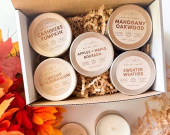 以下が含まれることがあります： Cashmere Pumpkin、Mahogany Oakwood、Apples + Maple Bourbon、Fireside Marshmallow、Sweater Weatherと書かれたラベルが貼られた、2オンス/57gのソイキャンドルが入った5つの丸い金属缶が、紙の詰め物と共に段ボールのギフトボックスに入っています。