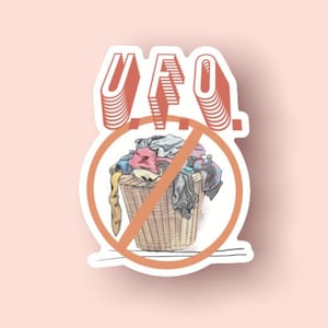 May include: A sticker with a red and white "UFO" text and a red circle with a diagonal line through it. Inside the circle is a brown wicker basket filled with colorful clothes.