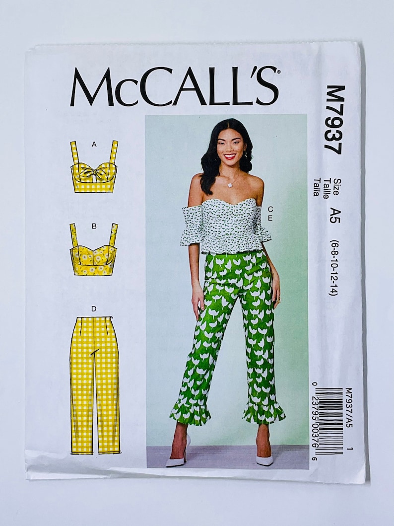 May include: A sewing pattern for a two-piece outfit. The pattern includes instructions for a crop top with a bow and a pair of wide-leg pants with a ruffle trim. The pattern is for sizes 6-8-10-12-14.