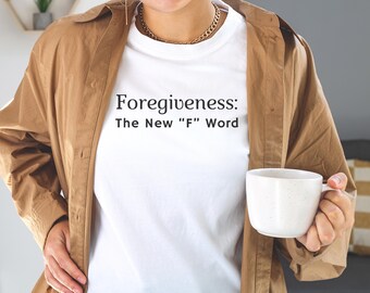 May include: A white t-shirt with the text "Forgiveness: The New "F" Word" printed on it. The person is wearing a brown jacket and holding a white mug.