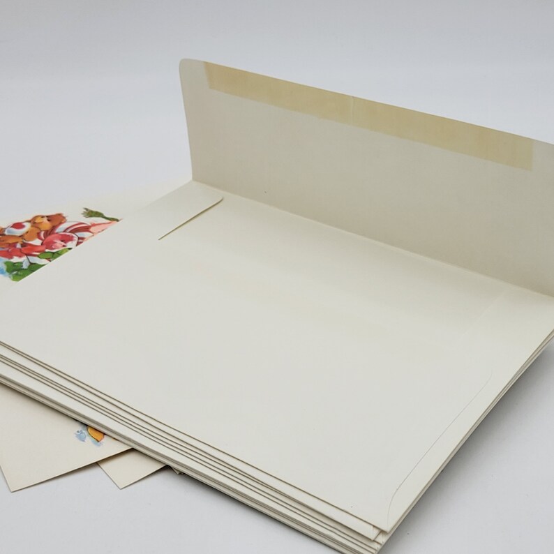 May include: A pile of cream-coloured envelopes, one with a floral design. The envelopes are open, showing the inside. The top envelope's flap is sealed with tape.