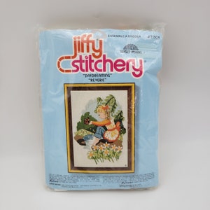May include: A Jiffy Stitchery embroidery kit featuring a girl daydreaming in a field of flowers. The kit is titled "Daydreaming" and "Reverie" and is labelled #715CN.
