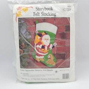 May include: A felt stocking craft kit featuring a Santa Claus and a puppy design. The kit includes stamped felt, embroidery floss, decorative trims, and instructions. The stocking is approximately 18 inches in diameter.