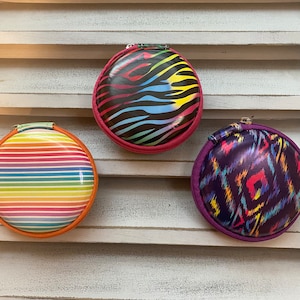 Peut inclure: Trois pochettes rondes &agrave; fermeture &eacute;clair avec diff&eacute;rents motifs color&eacute;s. Les pochettes sont en mati&egrave;re brillante et ont une fermeture &eacute;clair. Les motifs comprennent des rayures, un imprim&eacute; animal et un motif g&eacute;om&eacute;trique.