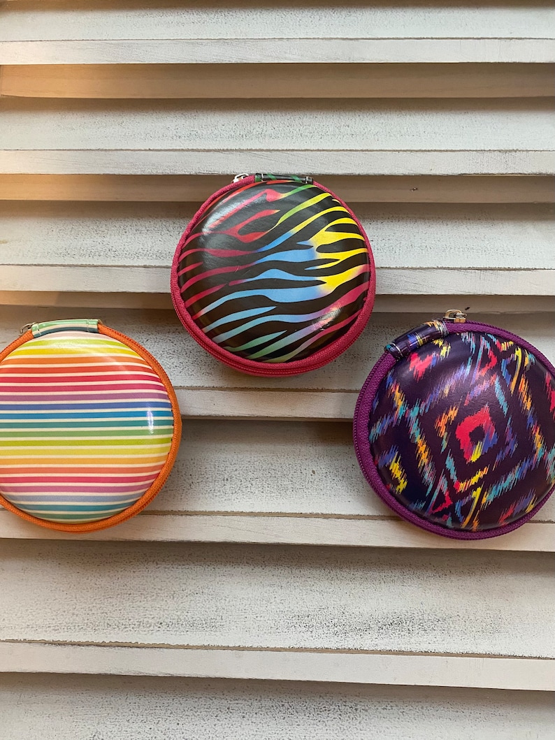 Peut inclure: Trois pochettes rondes &agrave; fermeture &eacute;clair avec diff&eacute;rents motifs color&eacute;s. Les pochettes sont en mati&egrave;re brillante et ont une fermeture &eacute;clair. Les motifs comprennent des rayures, un imprim&eacute; animal et un motif g&eacute;om&eacute;trique.