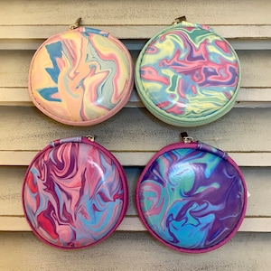 Peut inclure: Quatre pochettes rondes &agrave; fermeture &eacute;clair avec un motif en spirale dans des tons de rose, bleu et vert. Les pochettes sont en mati&egrave;re brillante et textur&eacute;e.