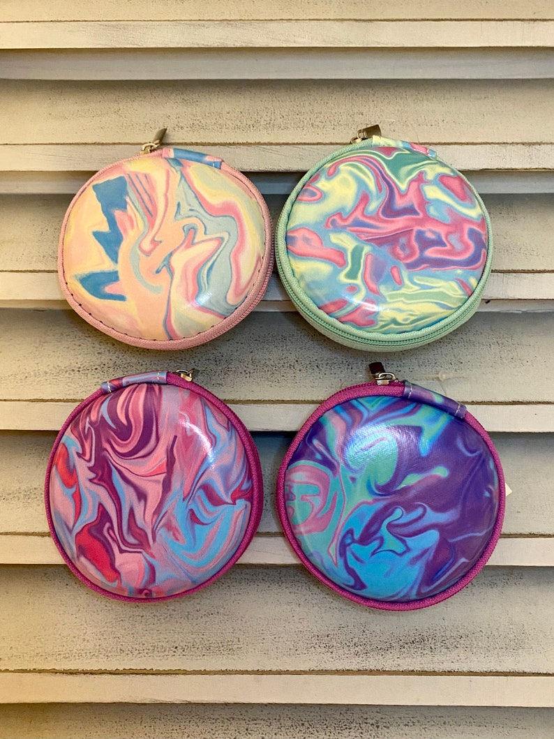 Peut inclure: Quatre pochettes rondes &agrave; fermeture &eacute;clair avec un motif en spirale dans des tons de rose, bleu et vert. Les pochettes sont en mati&egrave;re brillante et textur&eacute;e.