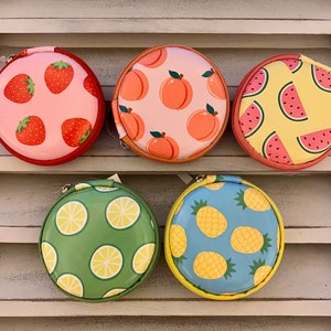 Peut inclure: Cinq pochettes rondes &agrave; fermeture &eacute;clair avec diff&eacute;rents motifs de fruits. Les pochettes sont roses avec des fraises, p&ecirc;che avec des p&ecirc;ches, jaunes avec des past&egrave;ques, vertes avec des citrons et bleues avec des ananas.