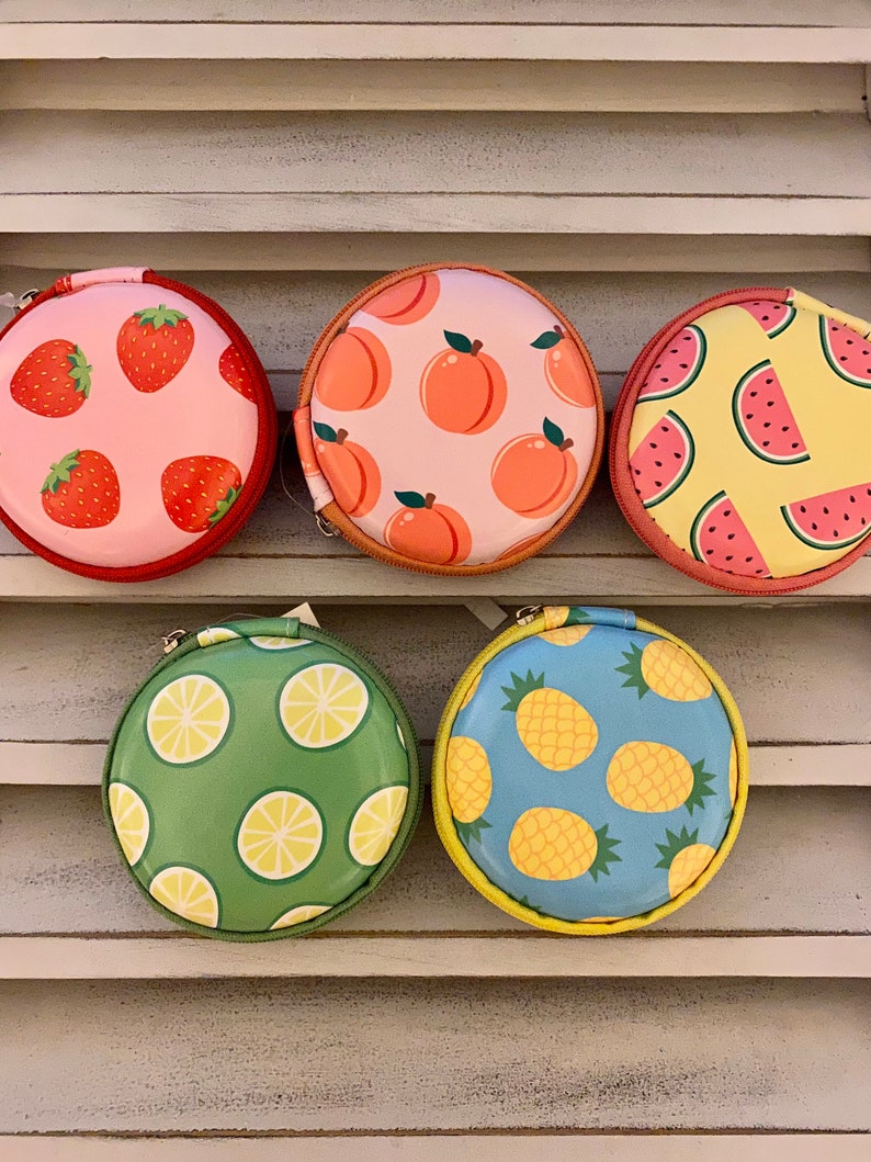Peut inclure: Cinq pochettes rondes &agrave; fermeture &eacute;clair avec diff&eacute;rents motifs de fruits. Les pochettes sont roses avec des fraises, p&ecirc;che avec des p&ecirc;ches, jaunes avec des past&egrave;ques, vertes avec des citrons et bleues avec des ananas.